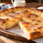 Bolla de nata gallega tradicional, con masa de pan dorada y cobertura de nata y azúcar, cortada en porciones sobre una tabla de madera.